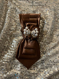 Chocolate brown satin tie with pearl and crystal brooch on silver sequin backdrop