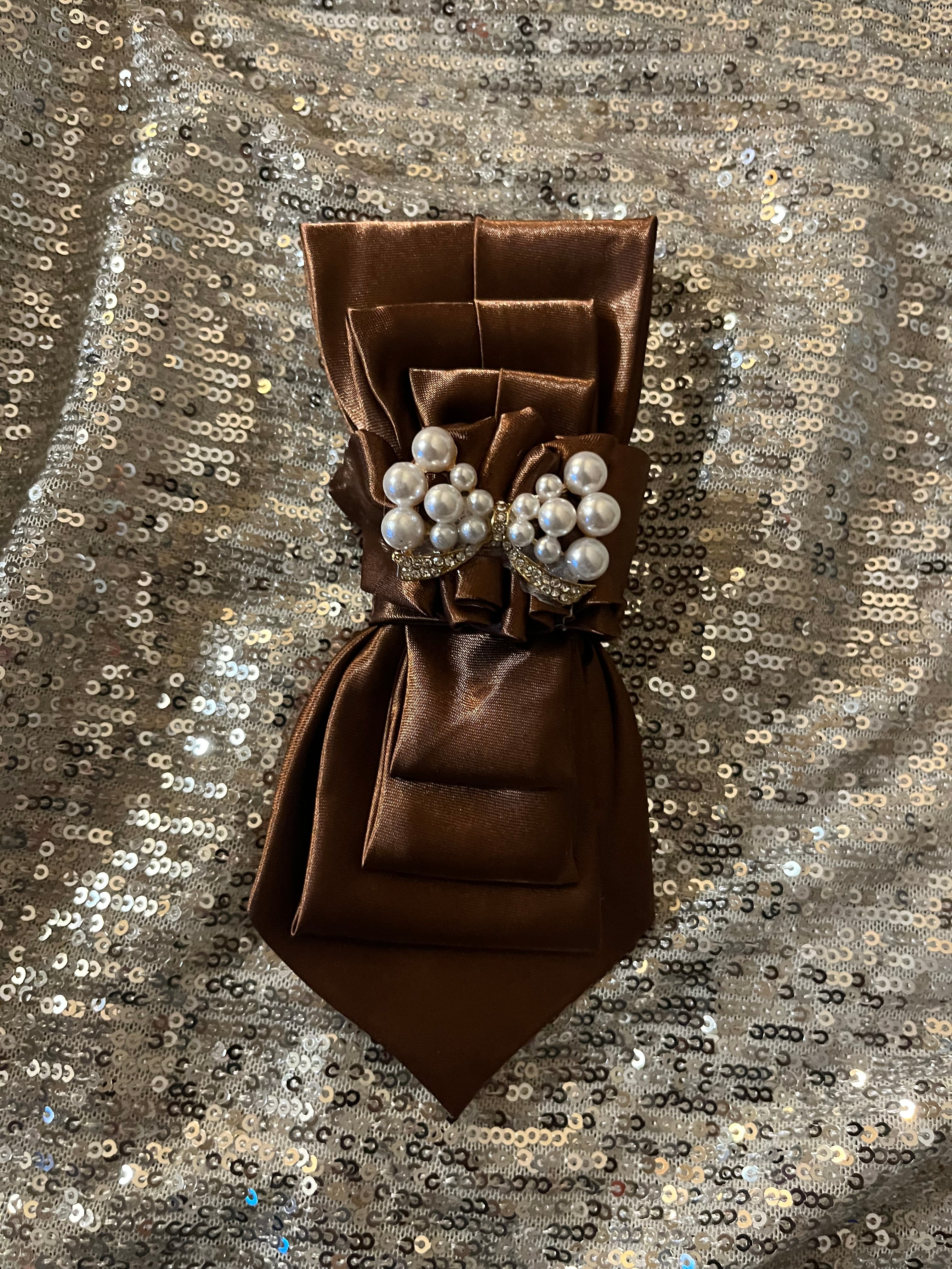Chocolate brown satin tie with pearl and crystal brooch on silver sequin backdrop
